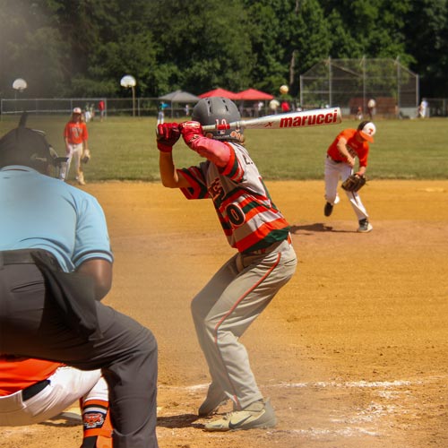 From over the shoulder of an umpire you can see a pitcher has thrown a pitch toward batter Logan Centineo, who is in his stance, loading and preparing to swing.