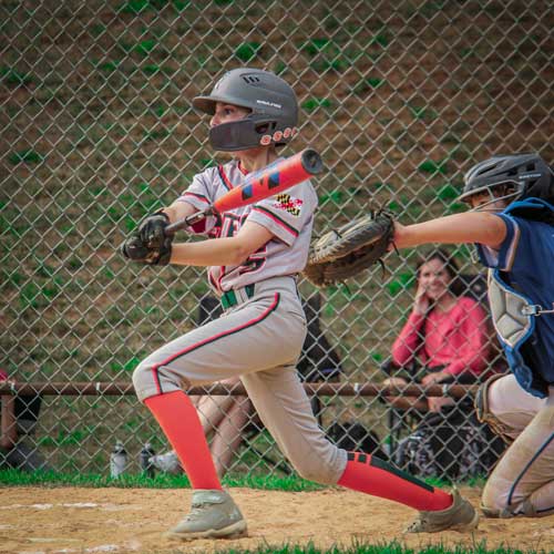 An Elkridge Hurricanes batter finishes his swing and prepares to run out of the batters box after hitting a line drive single to center field.