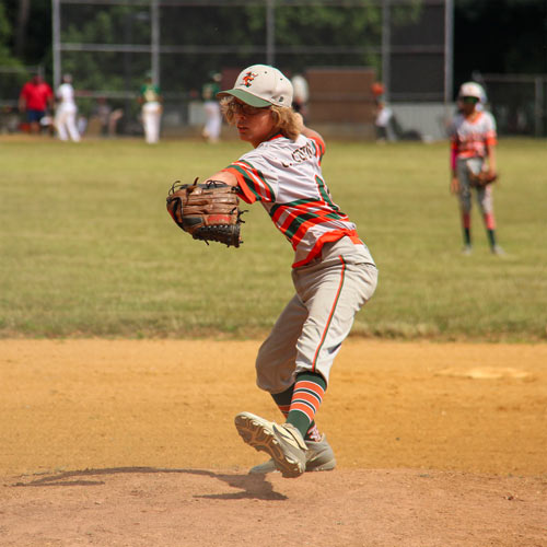 Pitcher Logan Centineo in his delivery, striding towards home and the camera with his arm cocked, ready to throw.